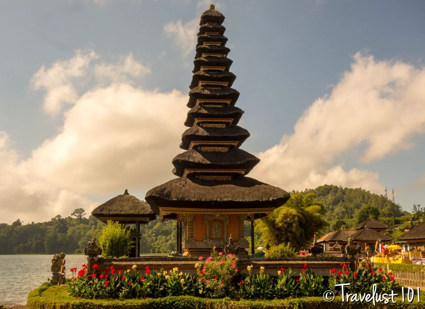 Close-up of the iconic 11-tiered meru tower of Pura Ulun Danu Beratan temple surrounded by flowers.