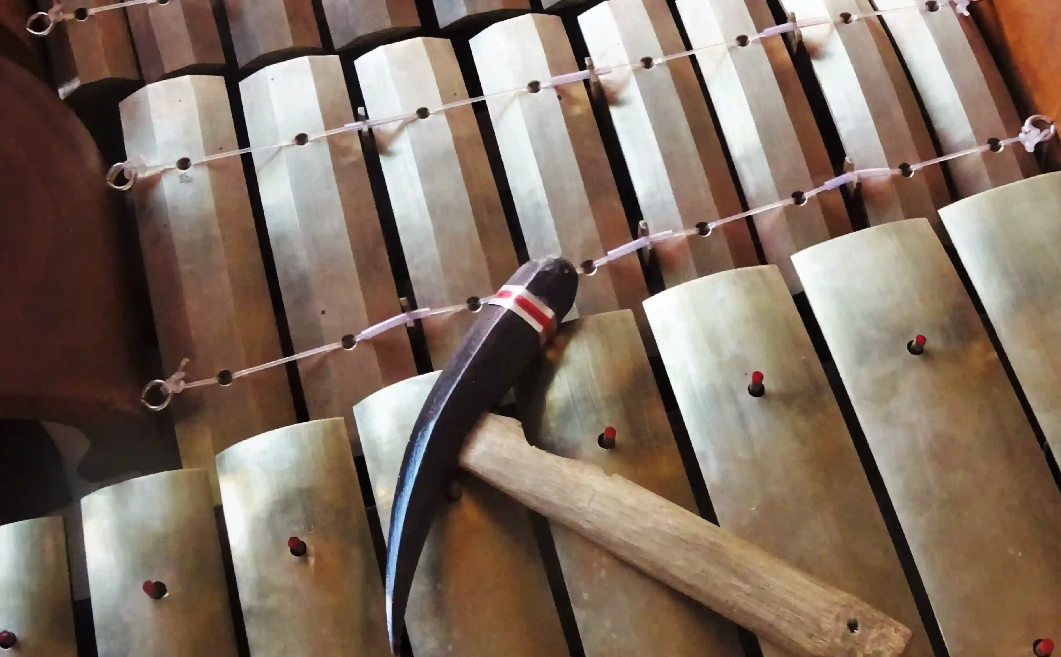 Close-up of a traditional Balinese Gamelan music instrument with a mallet resting on the keys.
