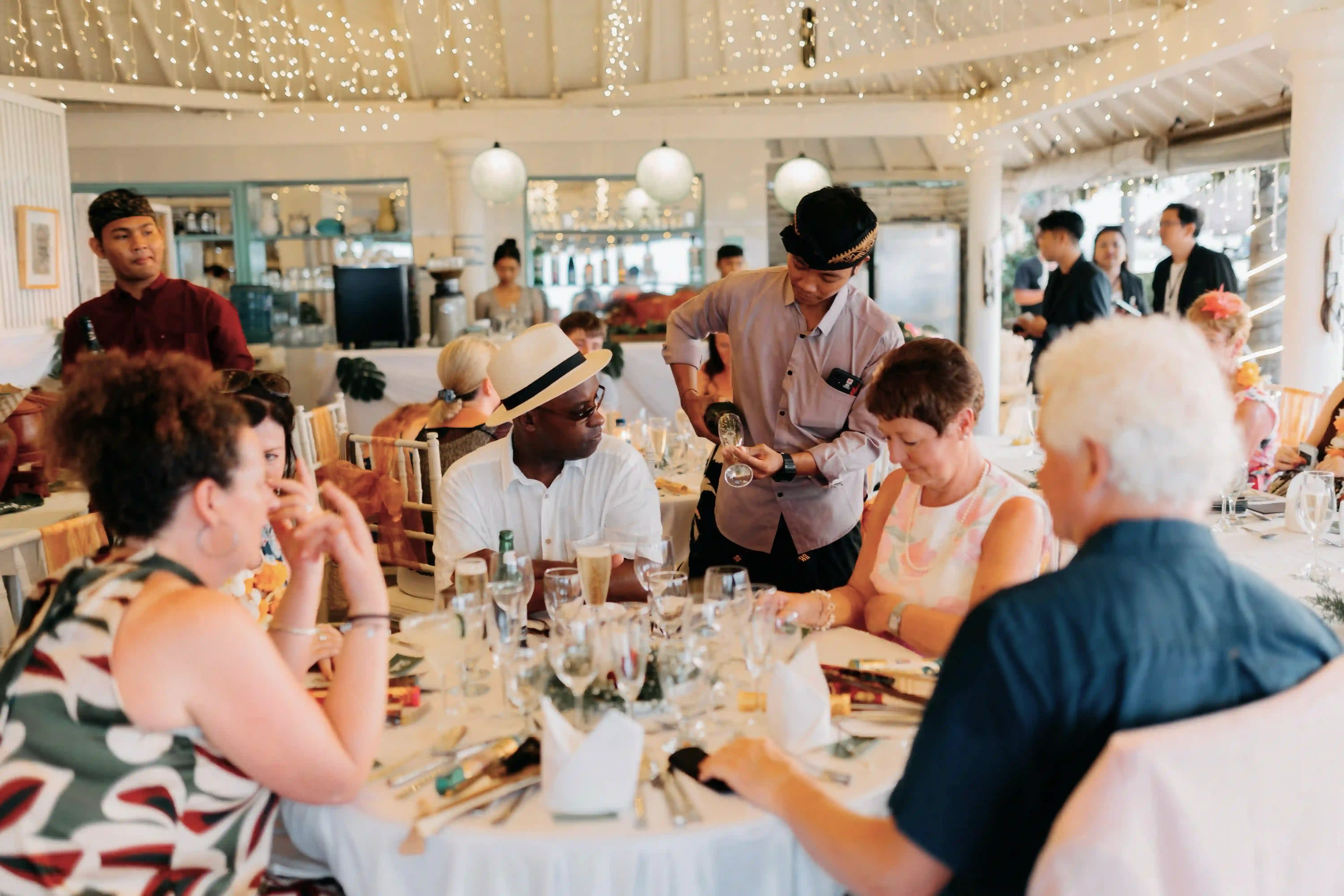 Guests celebrating a birthday or event indoors at the restaurant, with a waiter pouring wine.